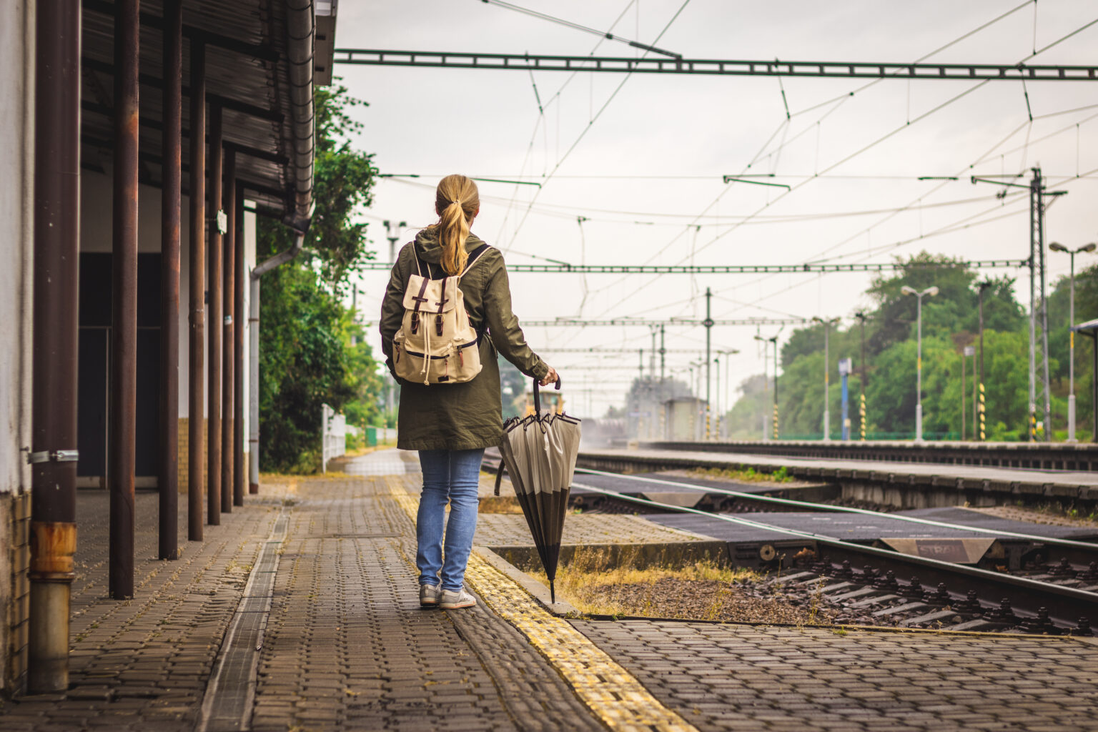 ragazza aspetta l'arrivo del treno in una stazione
